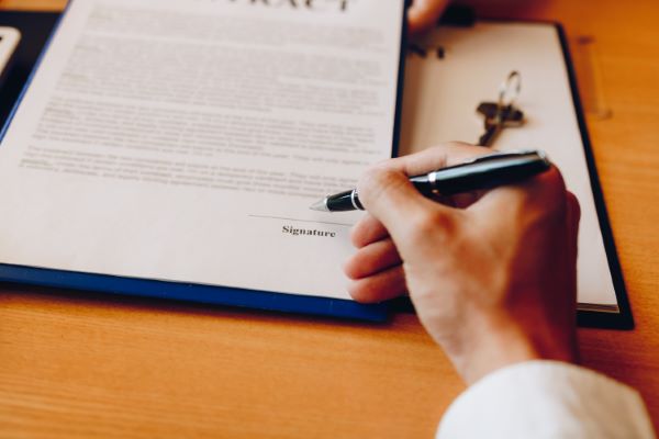 Traducción de documentos jurídicos; Acercamiento de un empleado firmando un contrato.